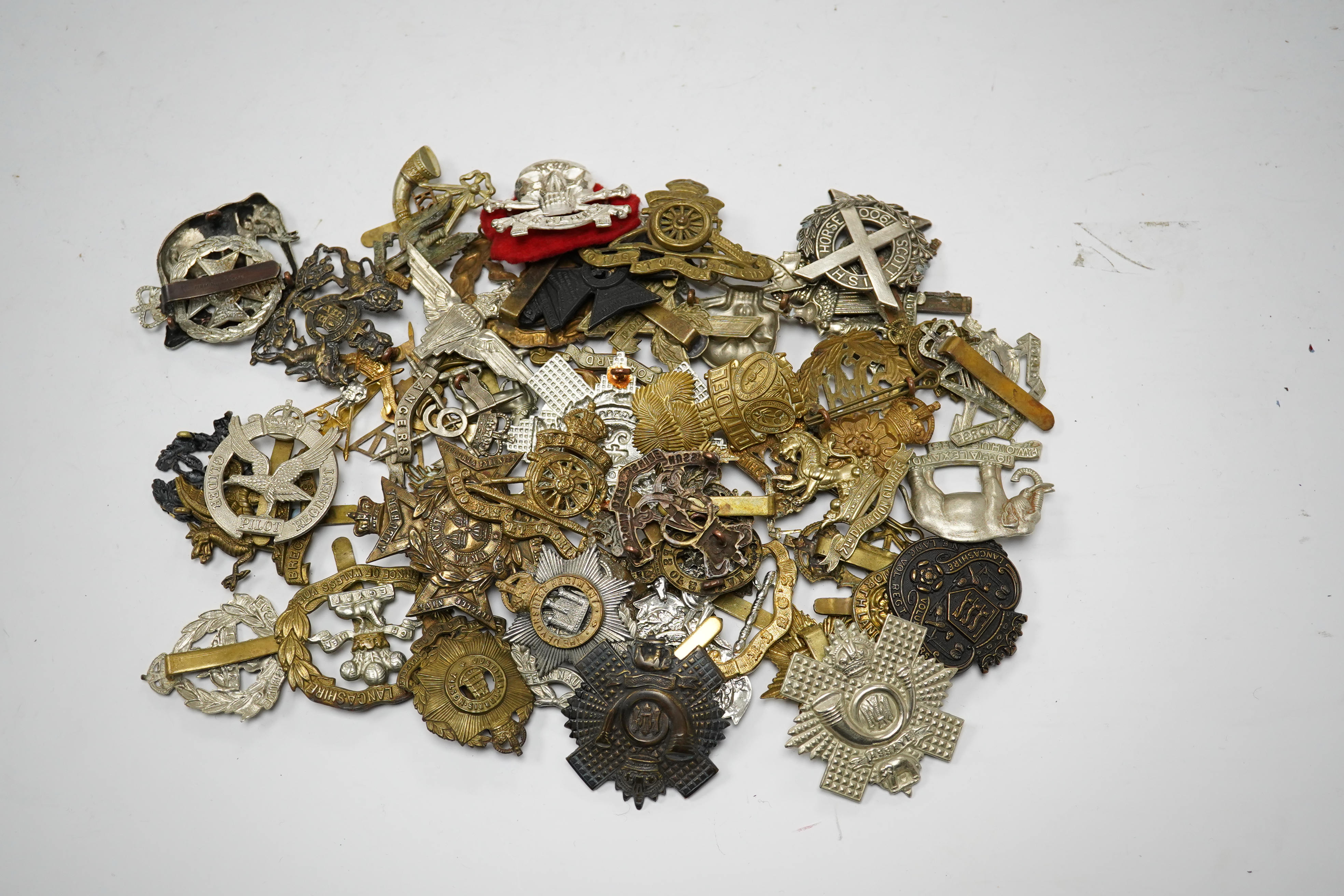 Sixty military cap badges, including; the Brecknockshire Regiment, the Royal Warwickshire Regiment, the South Lancashire Prince of Wales Volunteers, the Royal Artillery, the East Lancashire Regiment, the Glider Pilot Reg